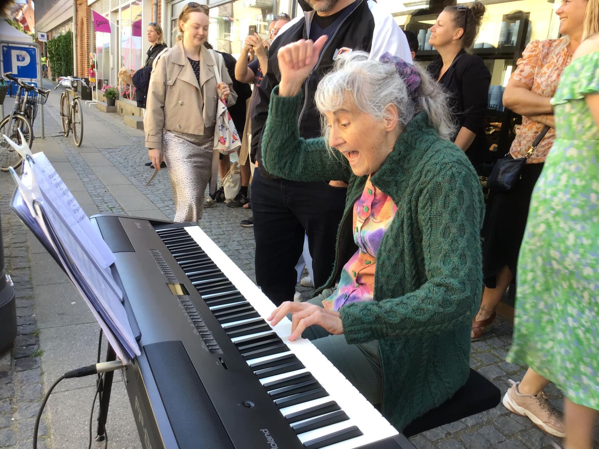 En ældre kvinde spiller et klaver på gaden.