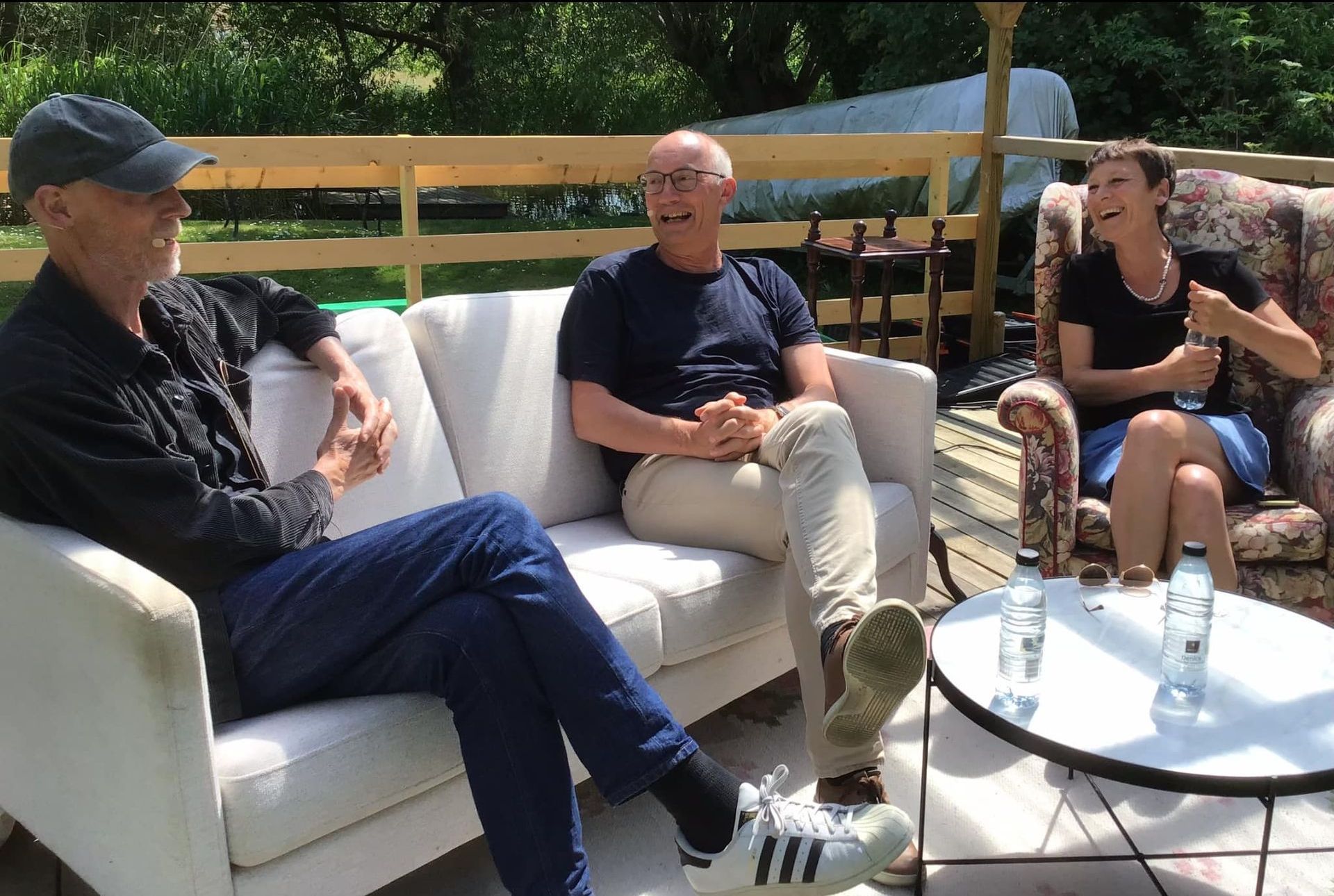 Tre personer sidder på en sofa og taler med hinanden