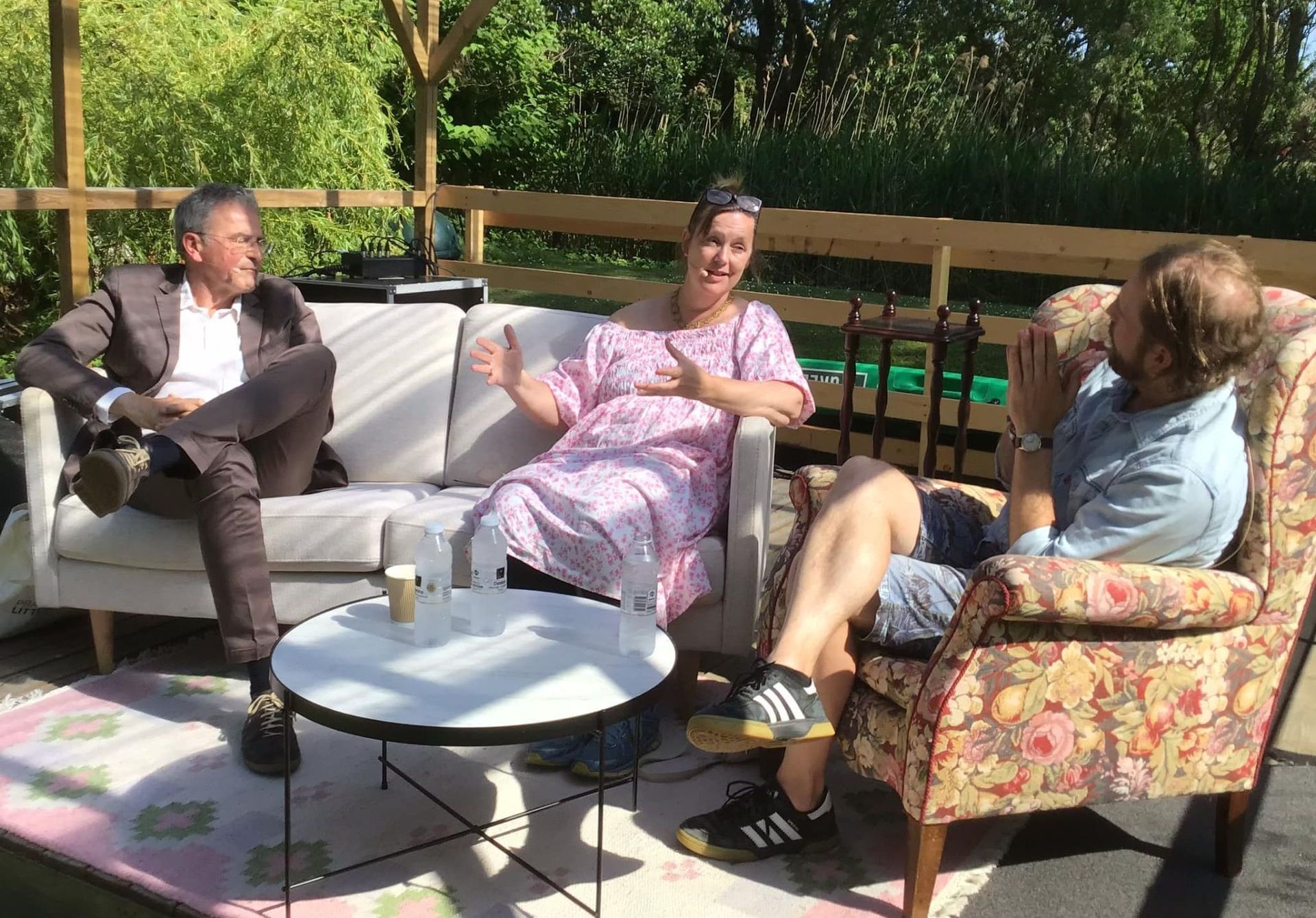 En gruppe mennesker sidder på en sofa og stole udenfor.