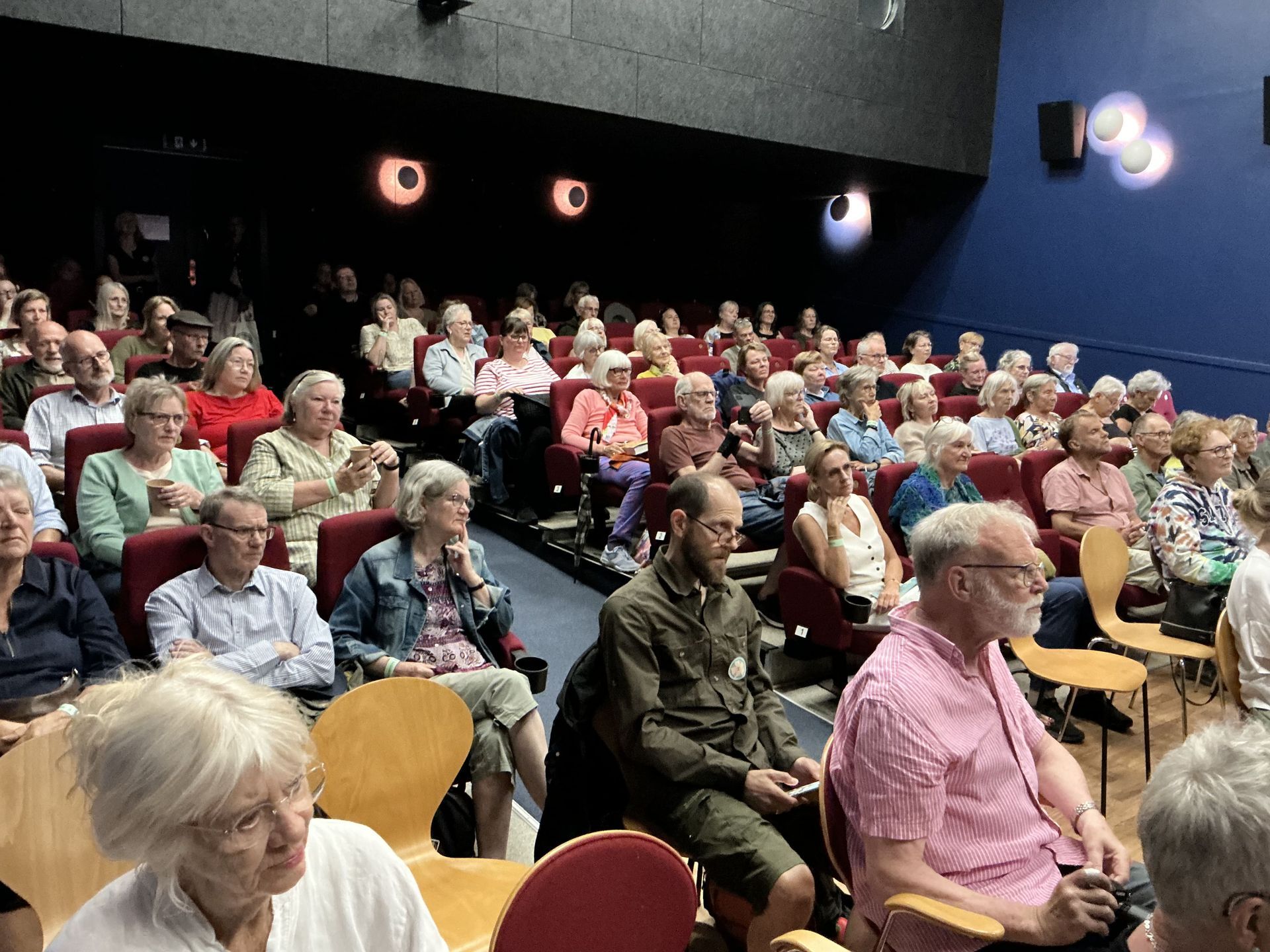 En stor gruppe mennesker sidder i en biograf og ser en film.