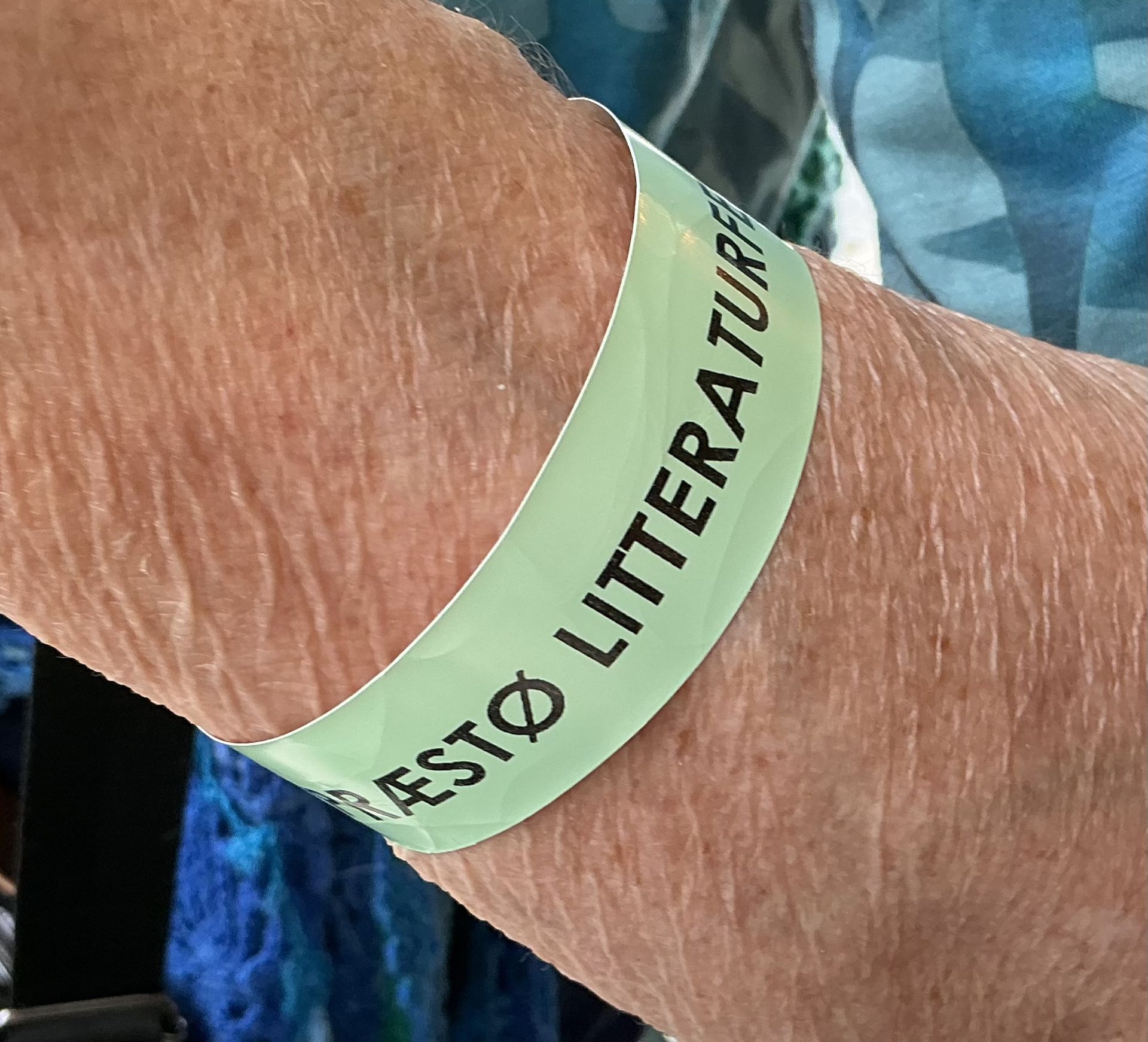 En person, der bærer et armbånd, hvorpå der står præstø litteraturfestival