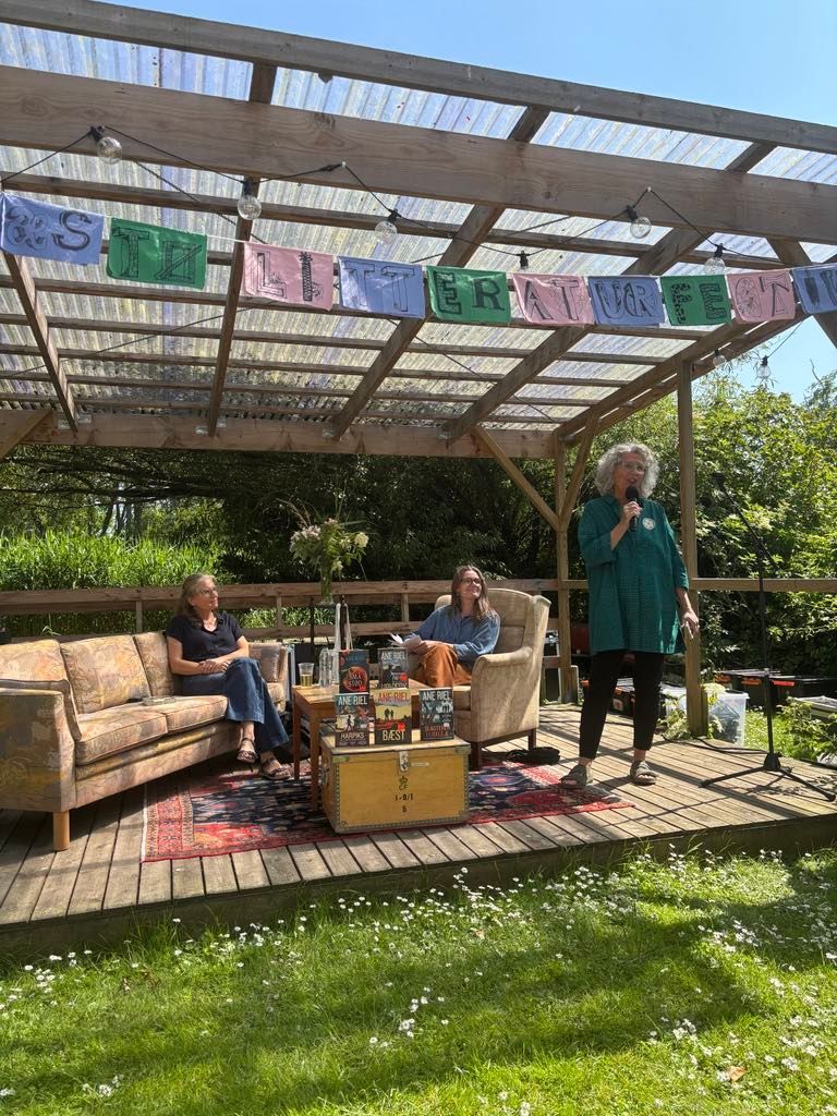 En gruppe mennesker sidder på en terrasse under en pergola.