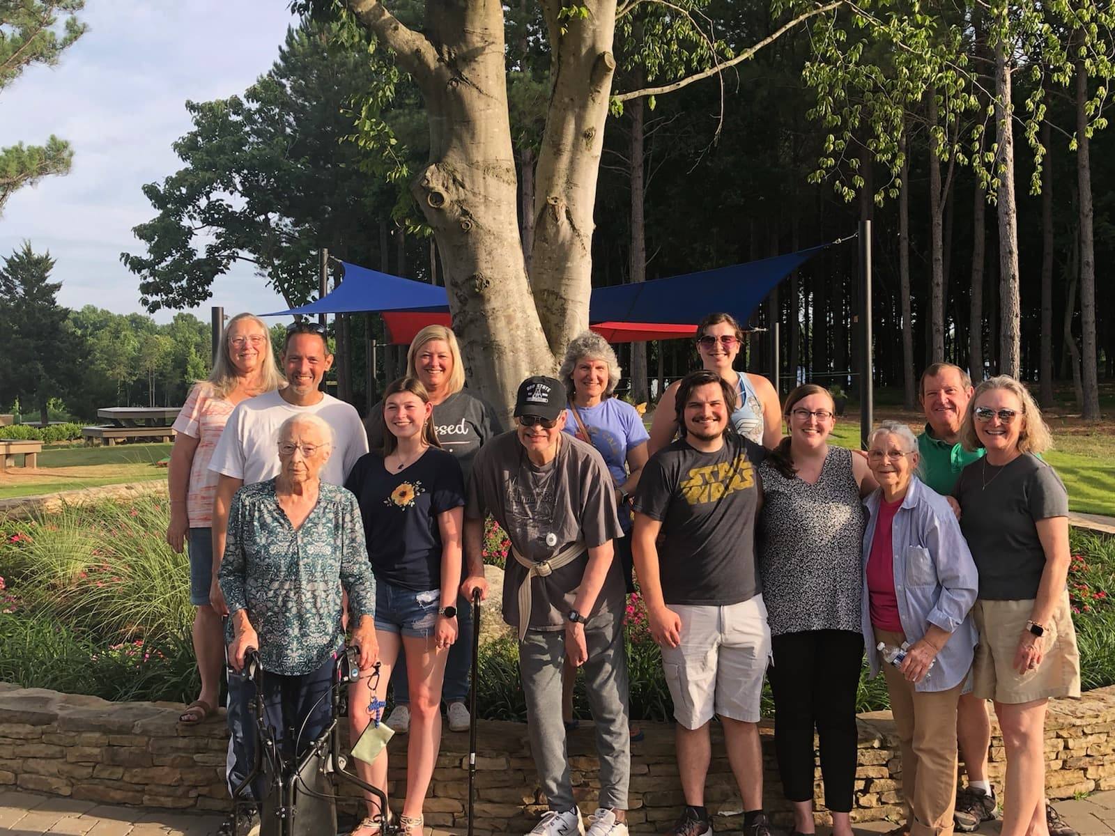 A group of people are posing for a picture in front of a tree.