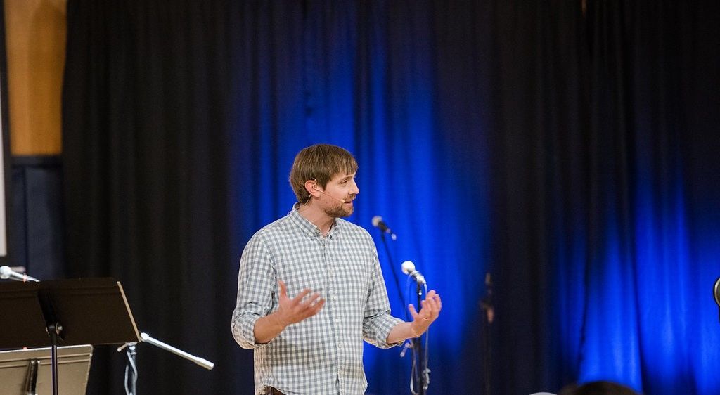A man is standing in front of a microphone on a stage.