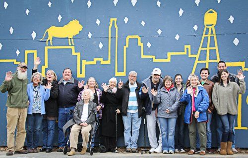 A group of people standing in front of a mural of a city skyline