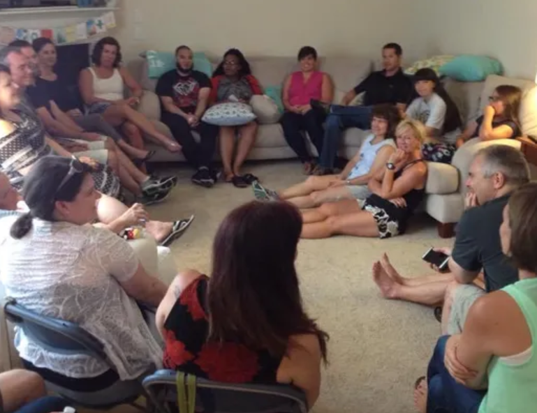 A group of people are sitting in a circle in a living room