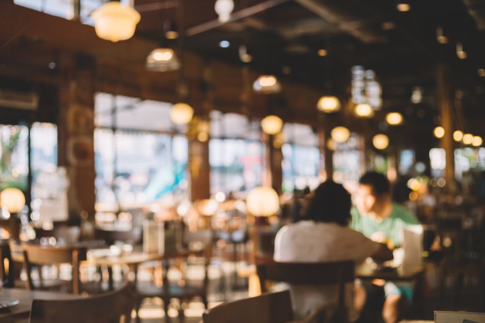 A blurry picture of people sitting at tables in a restaurant.