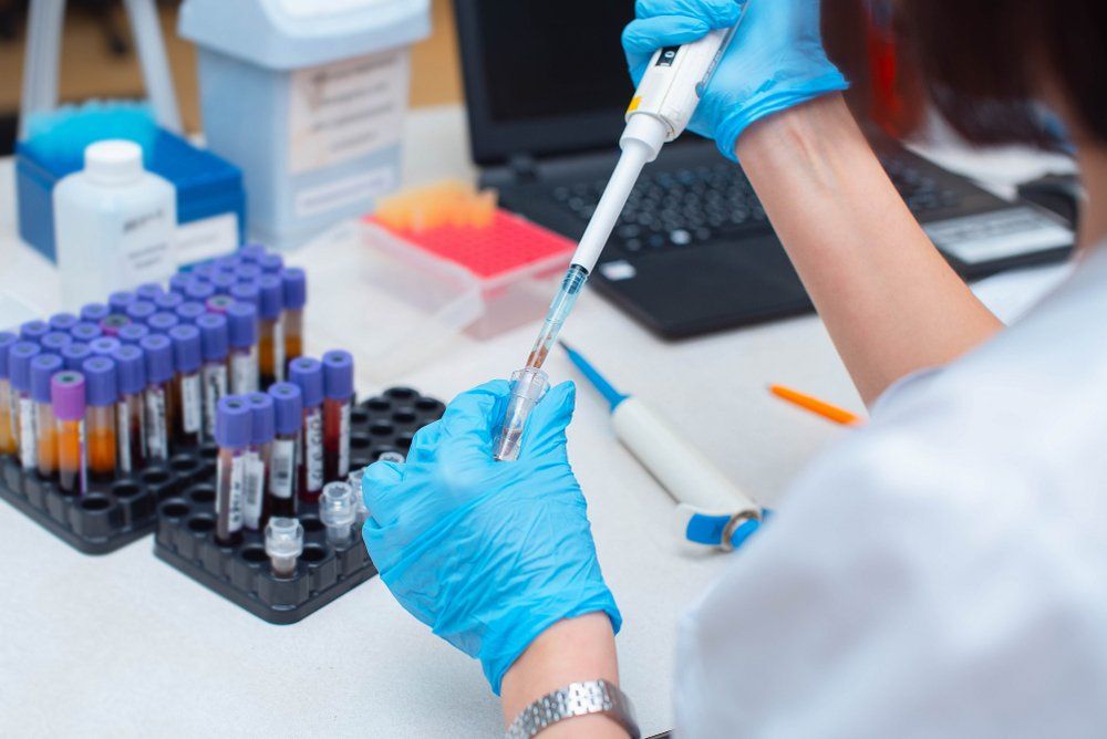 A scientist is using a pipette to pour liquid into a test tube.