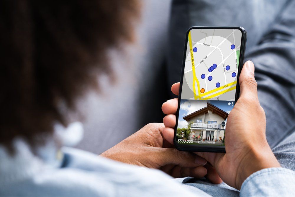 A person is holding a cell phone with a map and a picture of a house on it.