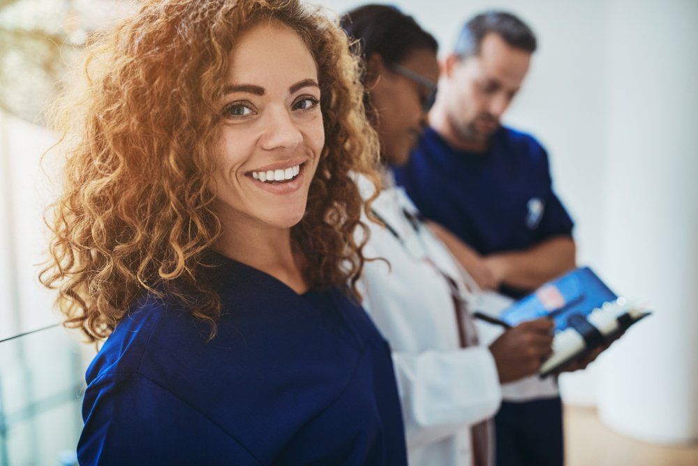 A group of doctors and nurses are standing next to each other and smiling.