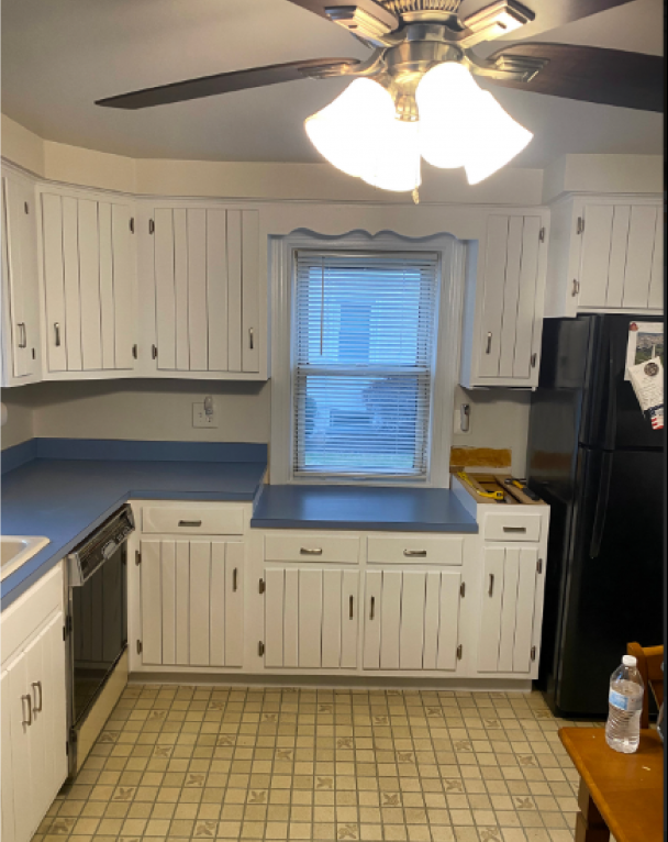 A kitchen with white cabinets and a black refrigerator
