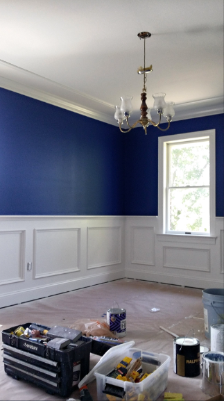 A room with blue walls and white trim is being painted