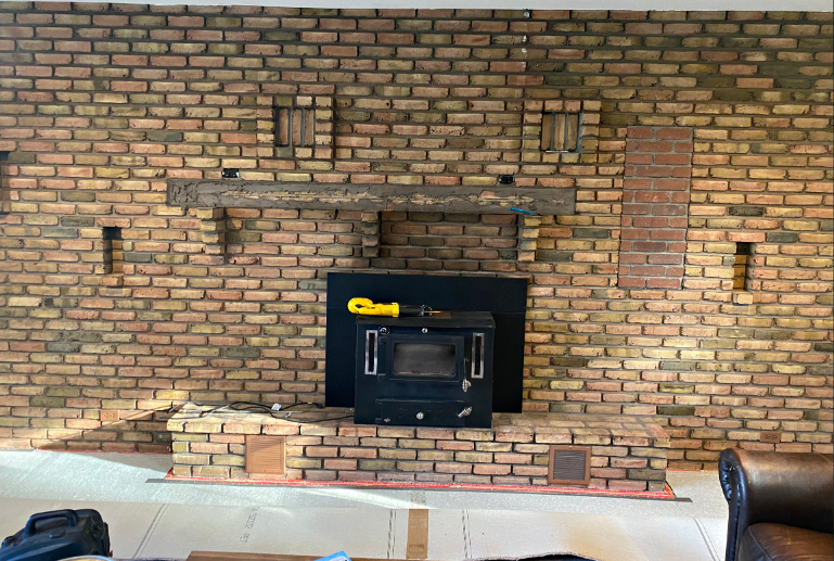 A living room with a brick fireplace and a wood stove.