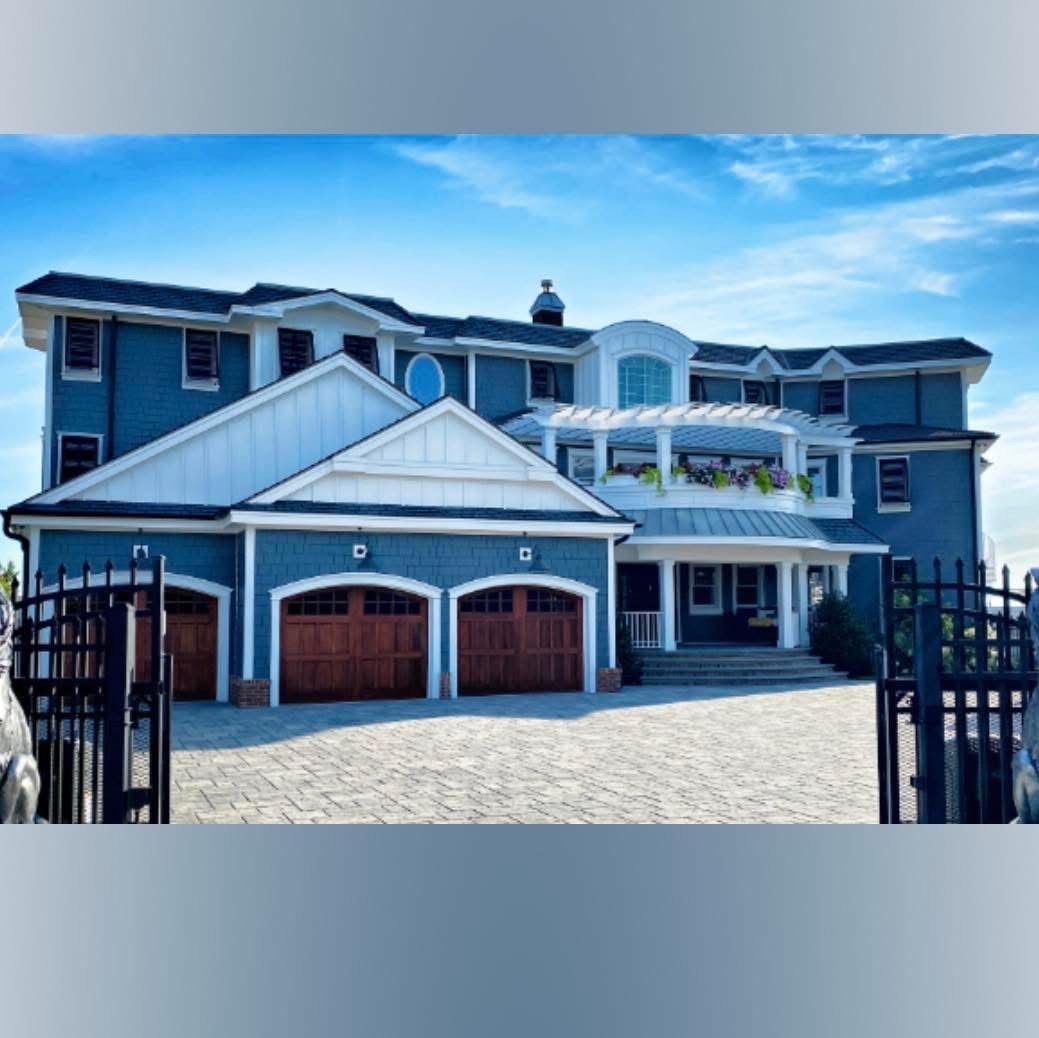 A large blue and white house with a fence in front of it
