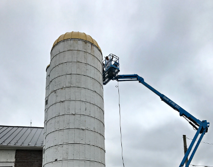 A man is working on a silo with a crane attached to it.