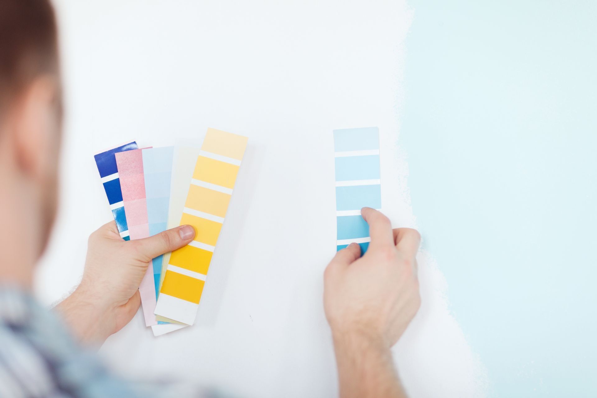 Hands comparing blue and yellow color swatches on a white background