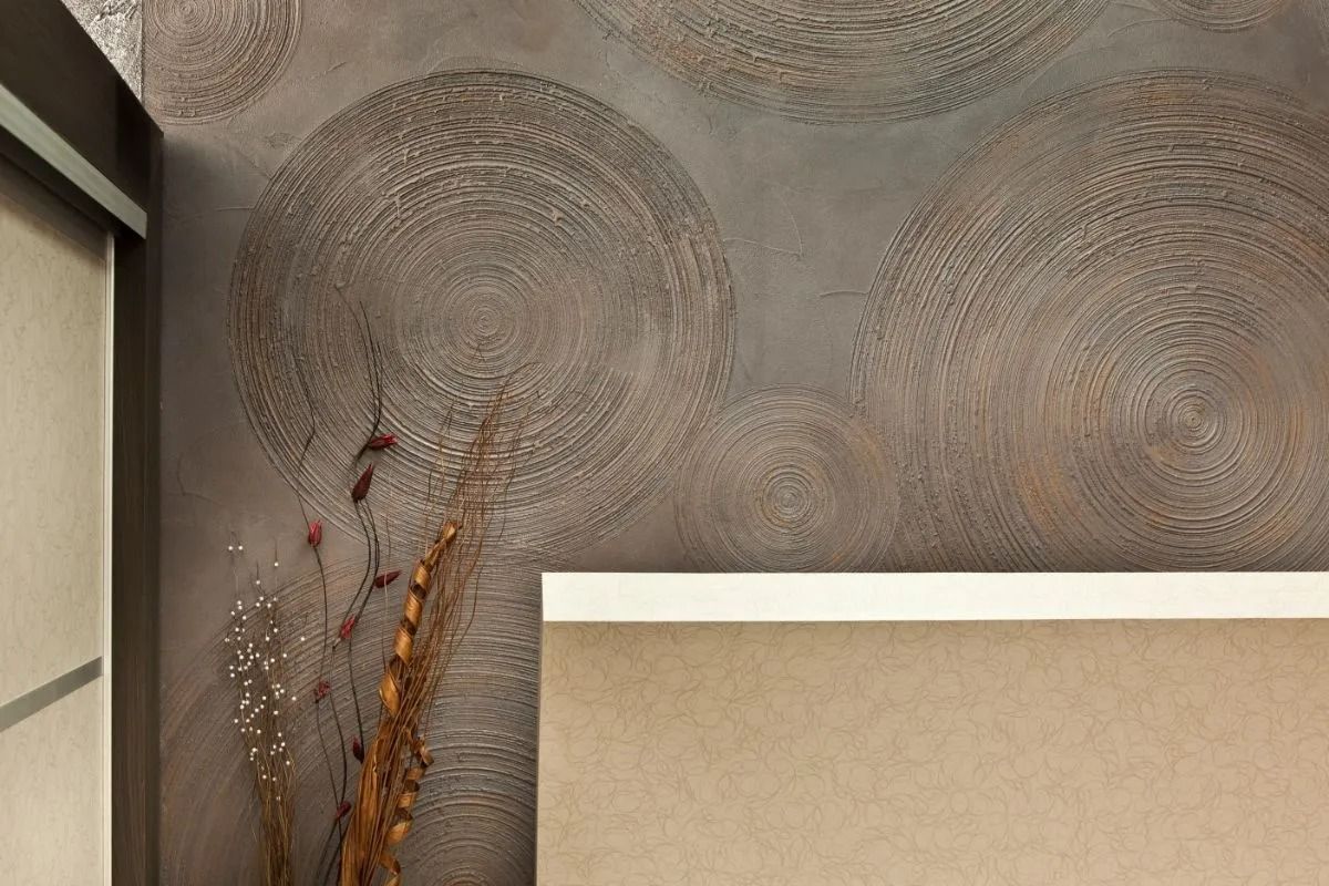 Abstract wall art with circular patterns and a beige upholstered chair in a modern interior