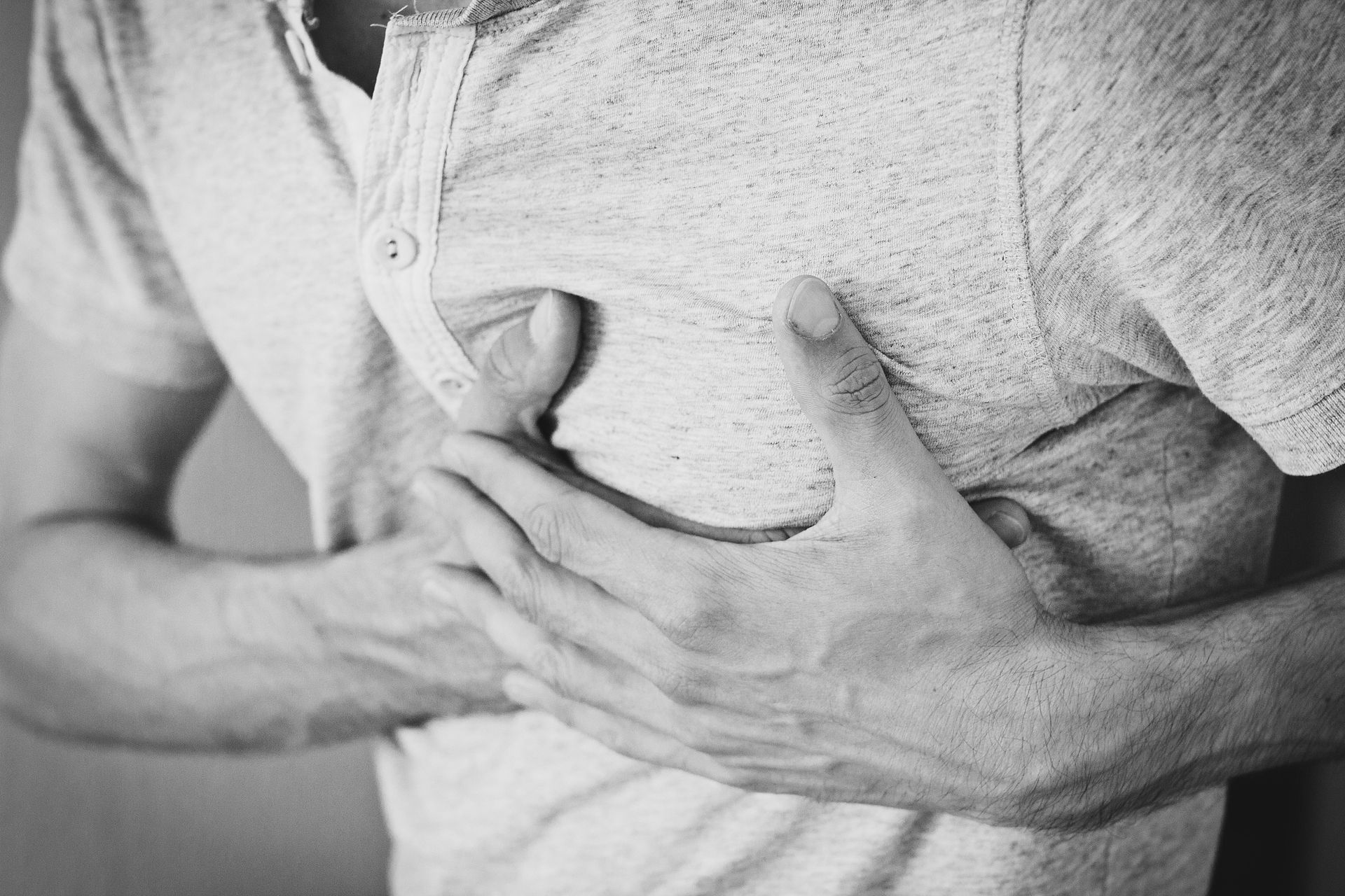Person clutching their chest with both hands, showing signs of chest pain.