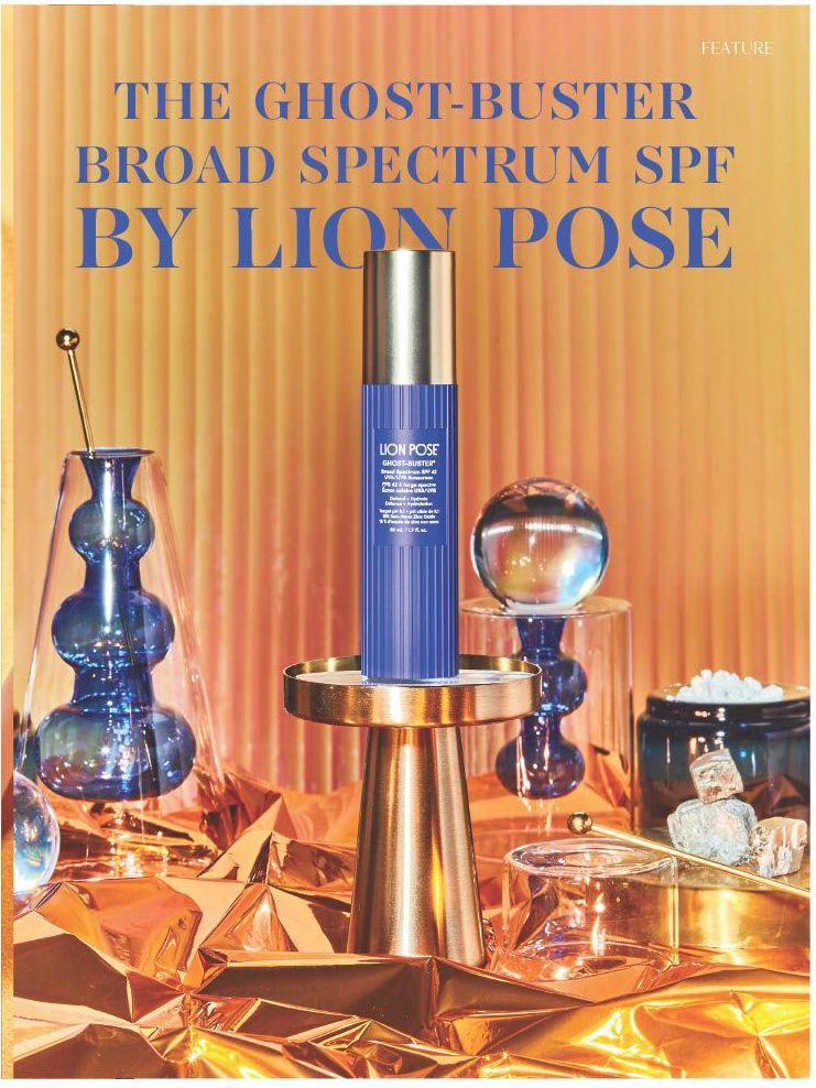 A royal blue bottle of Lion Pose's SPF with a shiny gold cap on an orange silk background