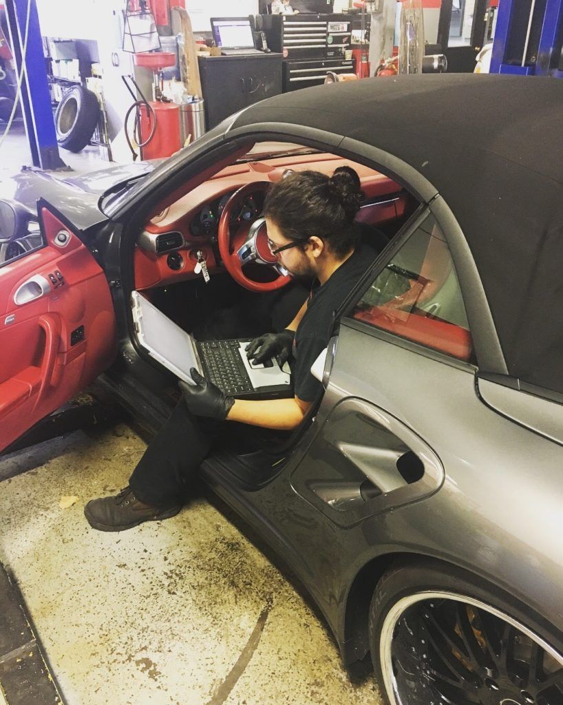 a mechanic is sitting in a car using a laptop