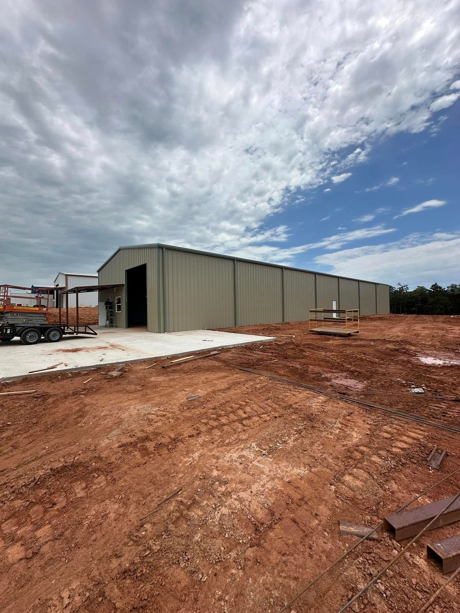 A large building is being built in a dirt field.