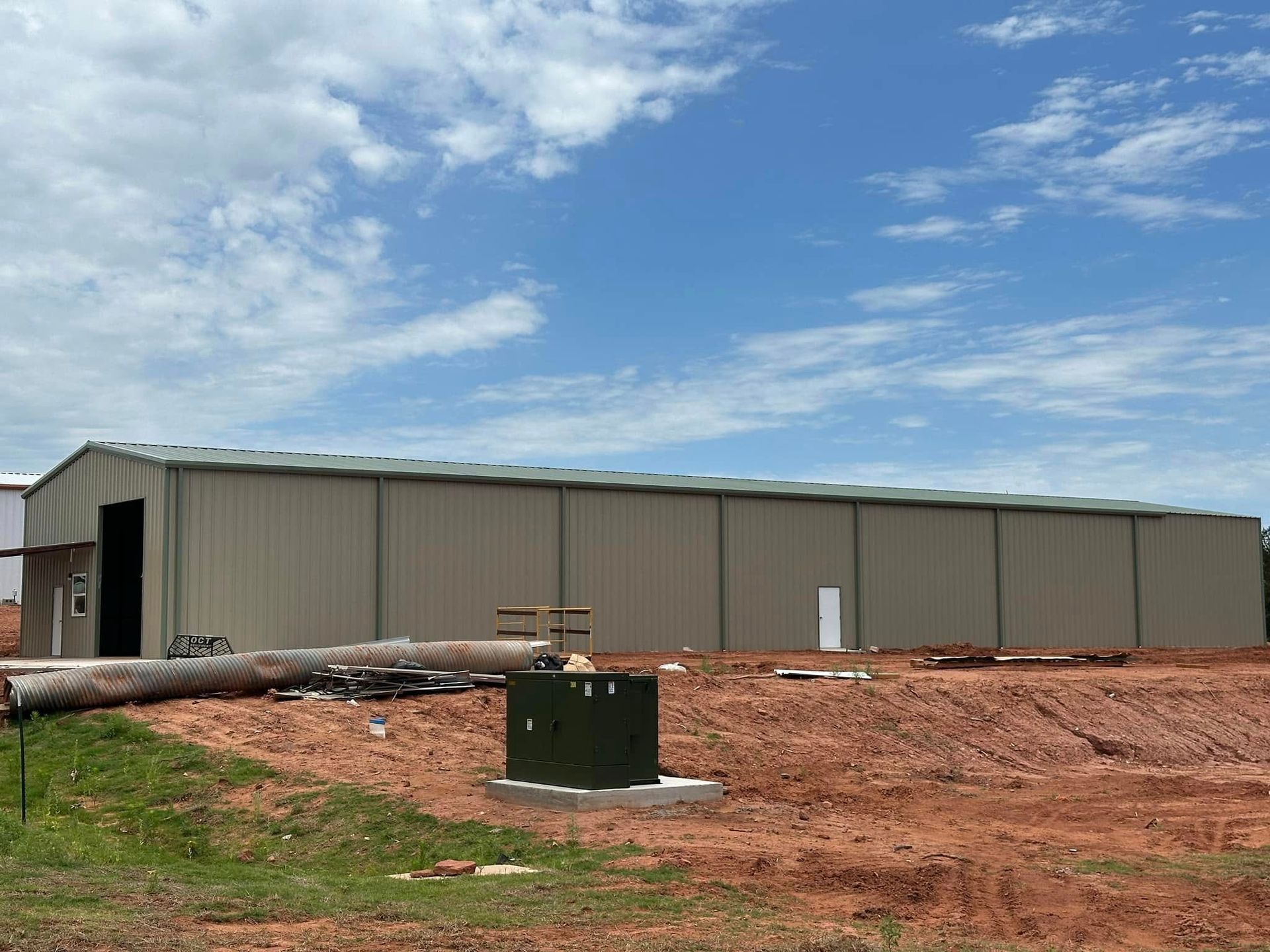 A large metal building is sitting in the middle of a dirt field.