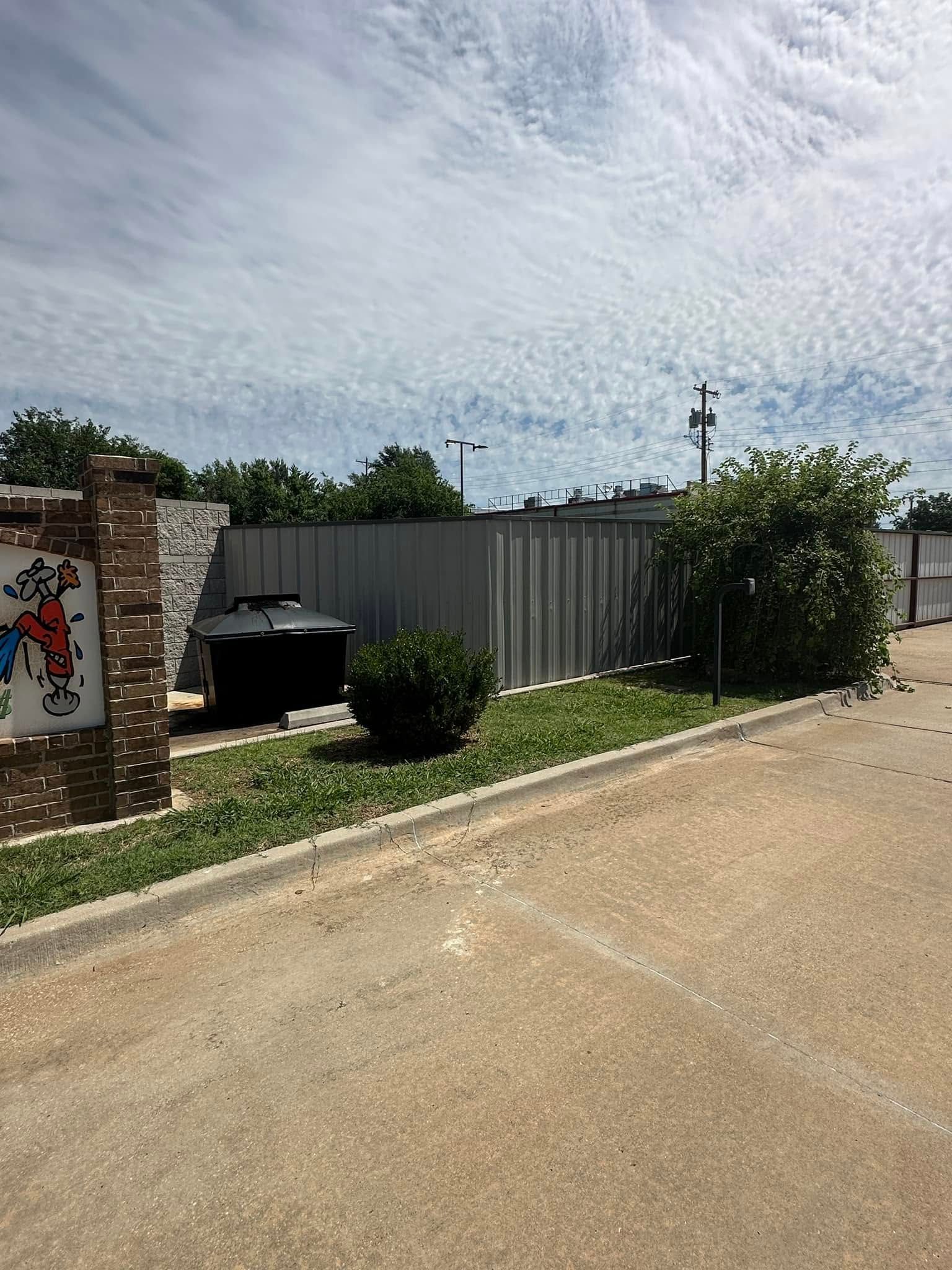 A dirt road with a fence and a sign on the side of it.