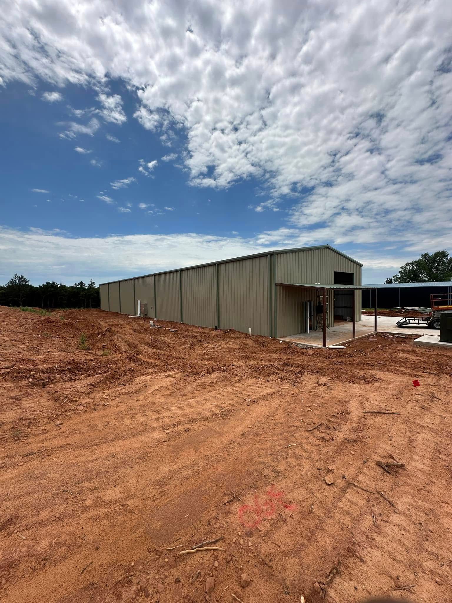 A large building is being built in the middle of a dirt field.