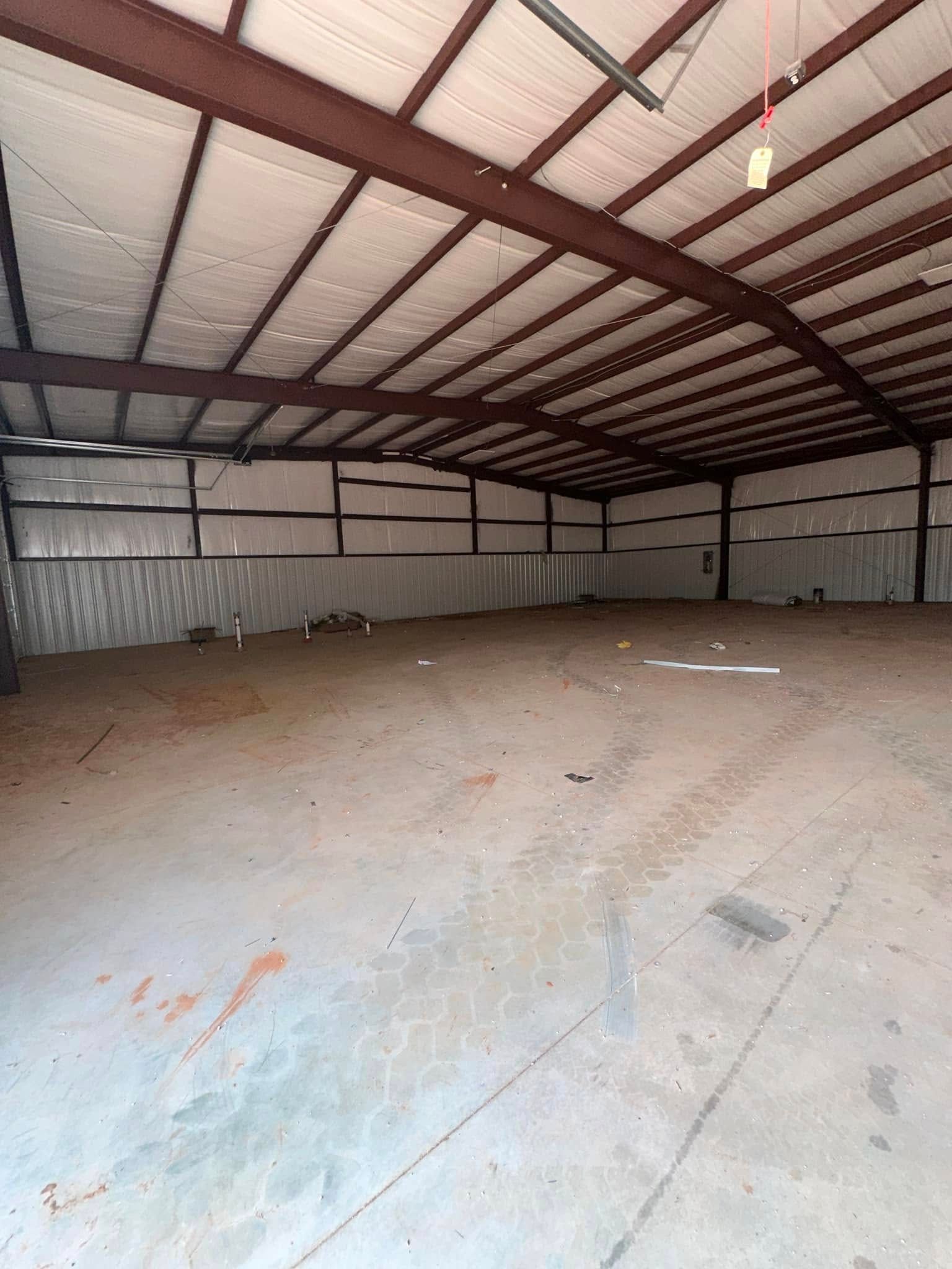 A large empty warehouse with a metal roof and a concrete floor.