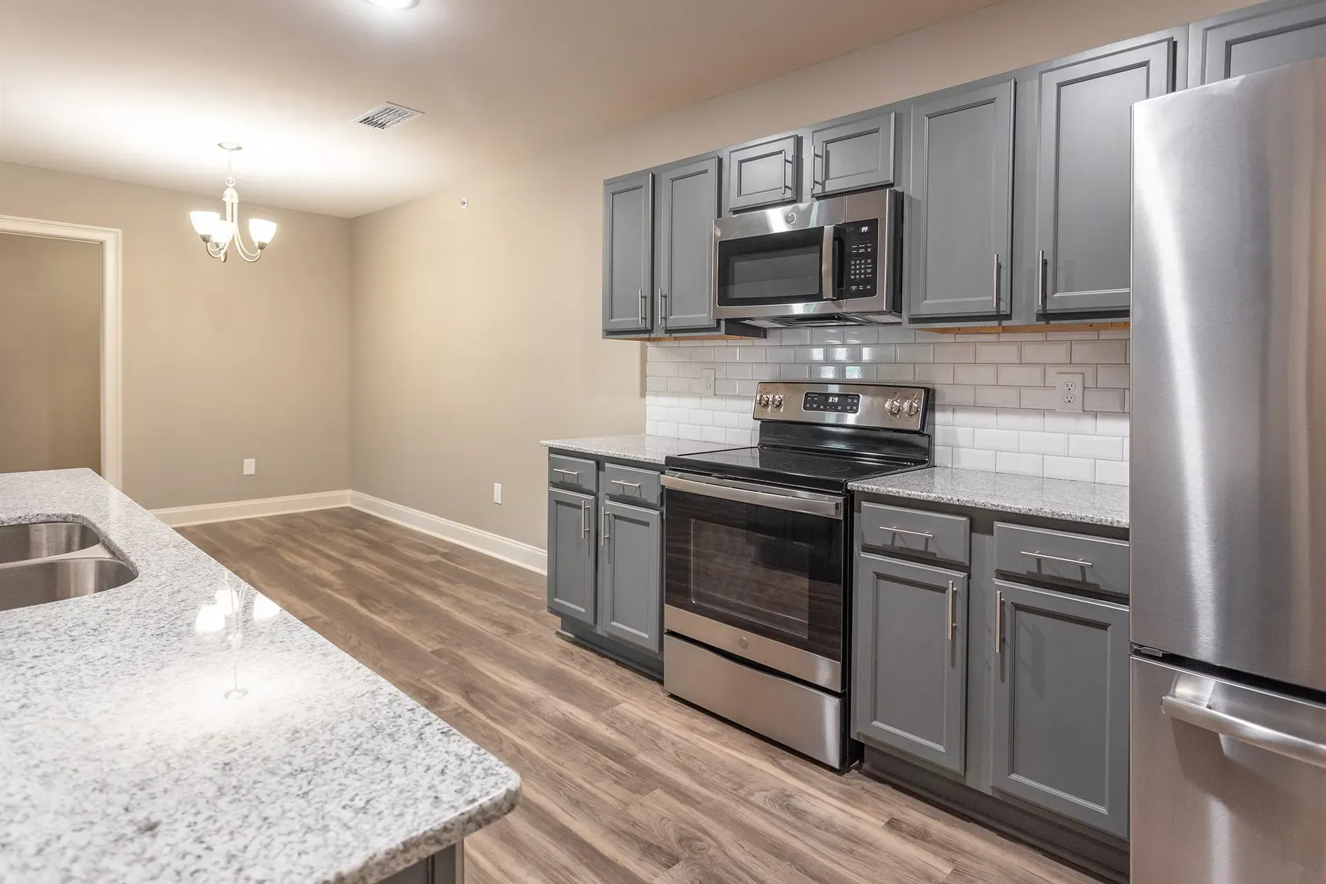 Modern kitchen with gray cabinets, stainless steel appliances, and a granite countertop.
