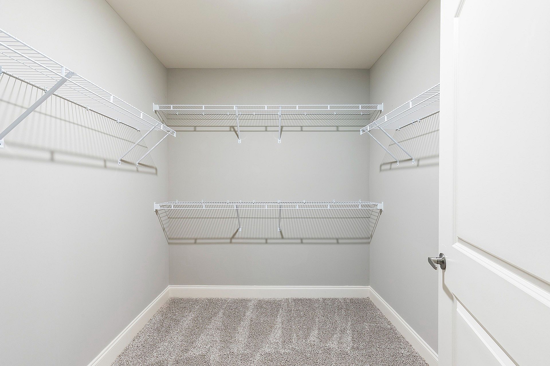 Empty walk-in closet with white wire shelves along the walls.