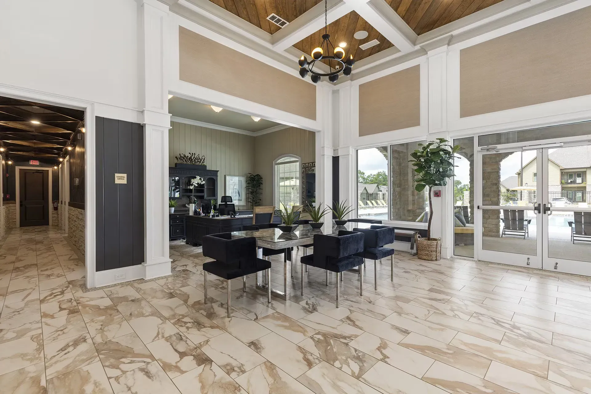 Lobby with marble floors, seating area with dark chairs, and large windows leading outside.