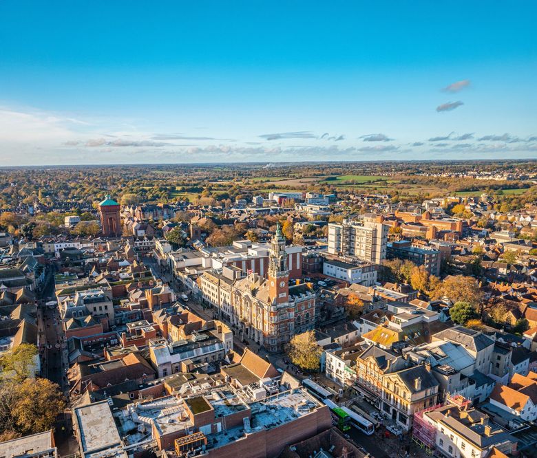 Aerial view of a historic city center with brick buildings and streets under a clear blue sky