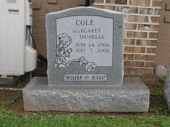 Grave marker for Margaret Danielle Cole: grey stone with name, dates (2002), and kneeling child image. 