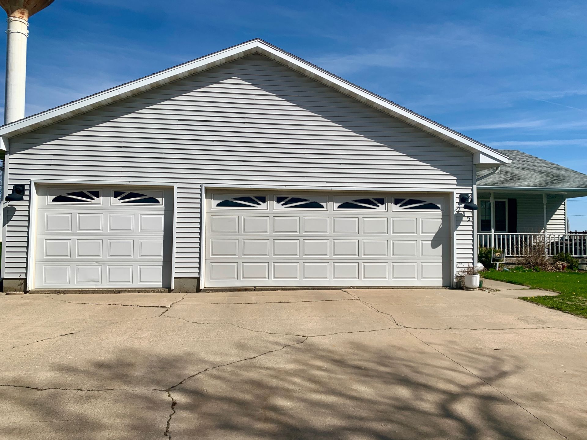 Two-car garage with white doors and a gray roof, in front of a blue sky.
