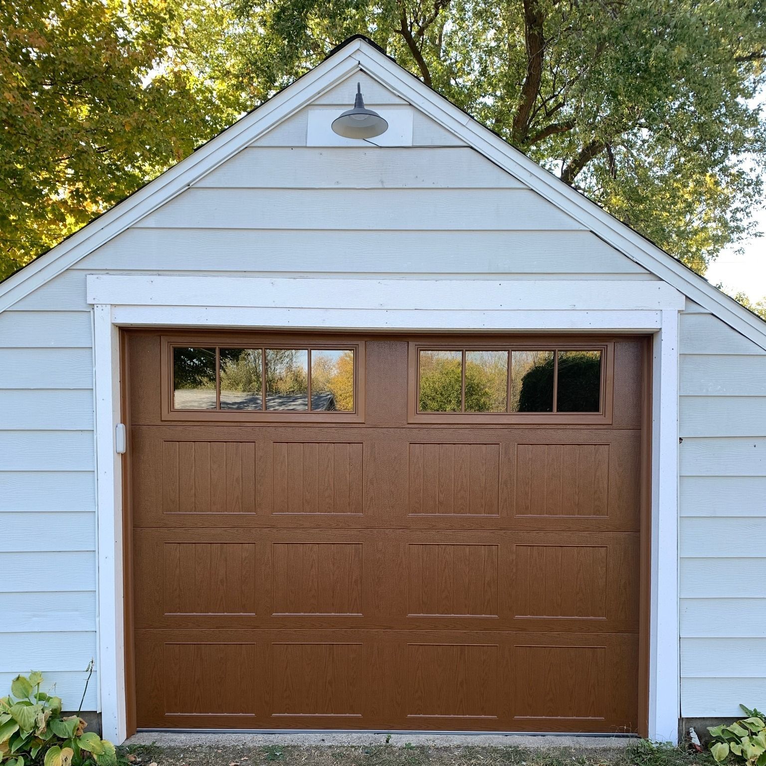 Brown garage door with two windows, set in a light blue garage.