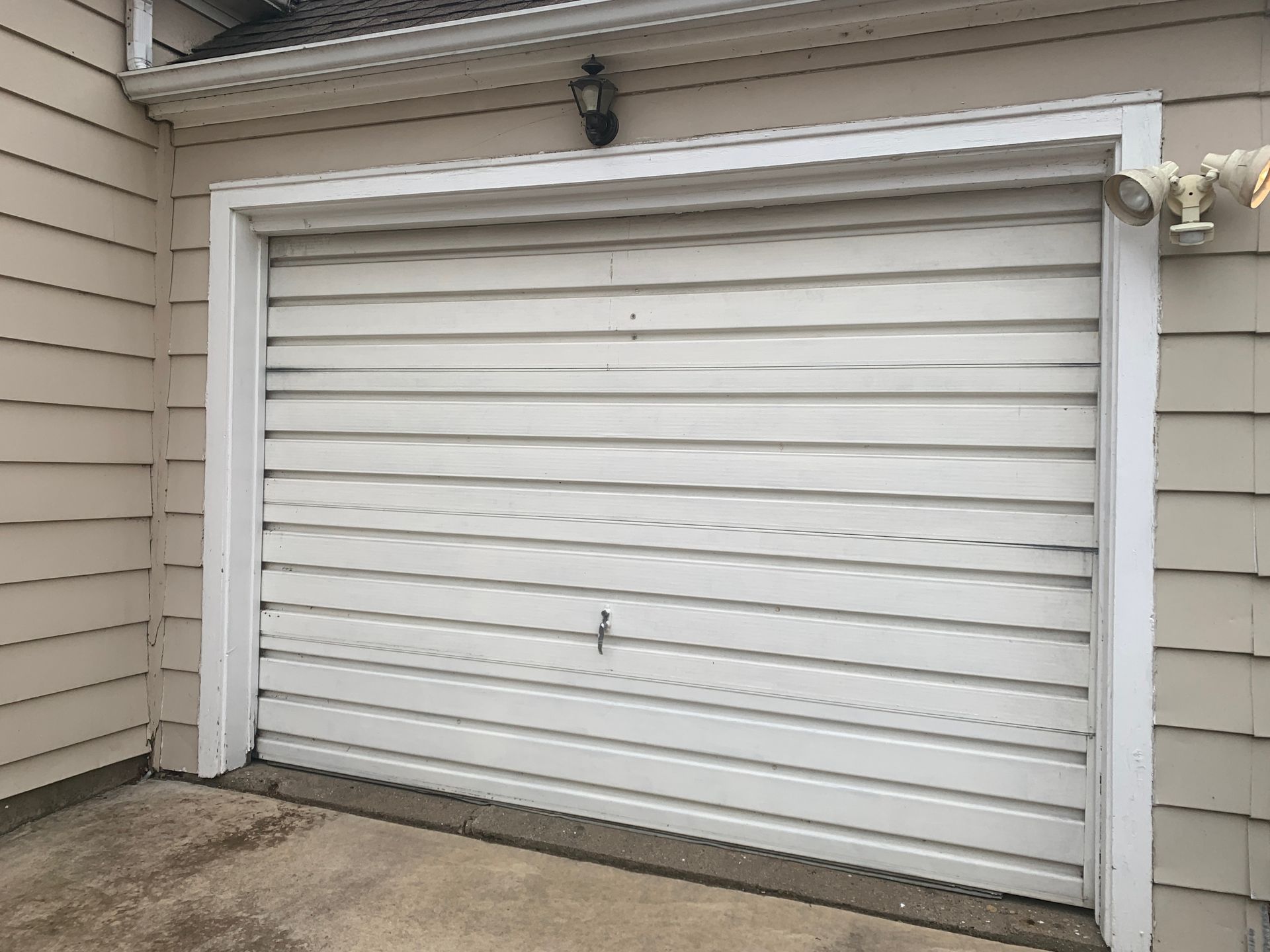 White garage door, light beige siding, concrete driveway.