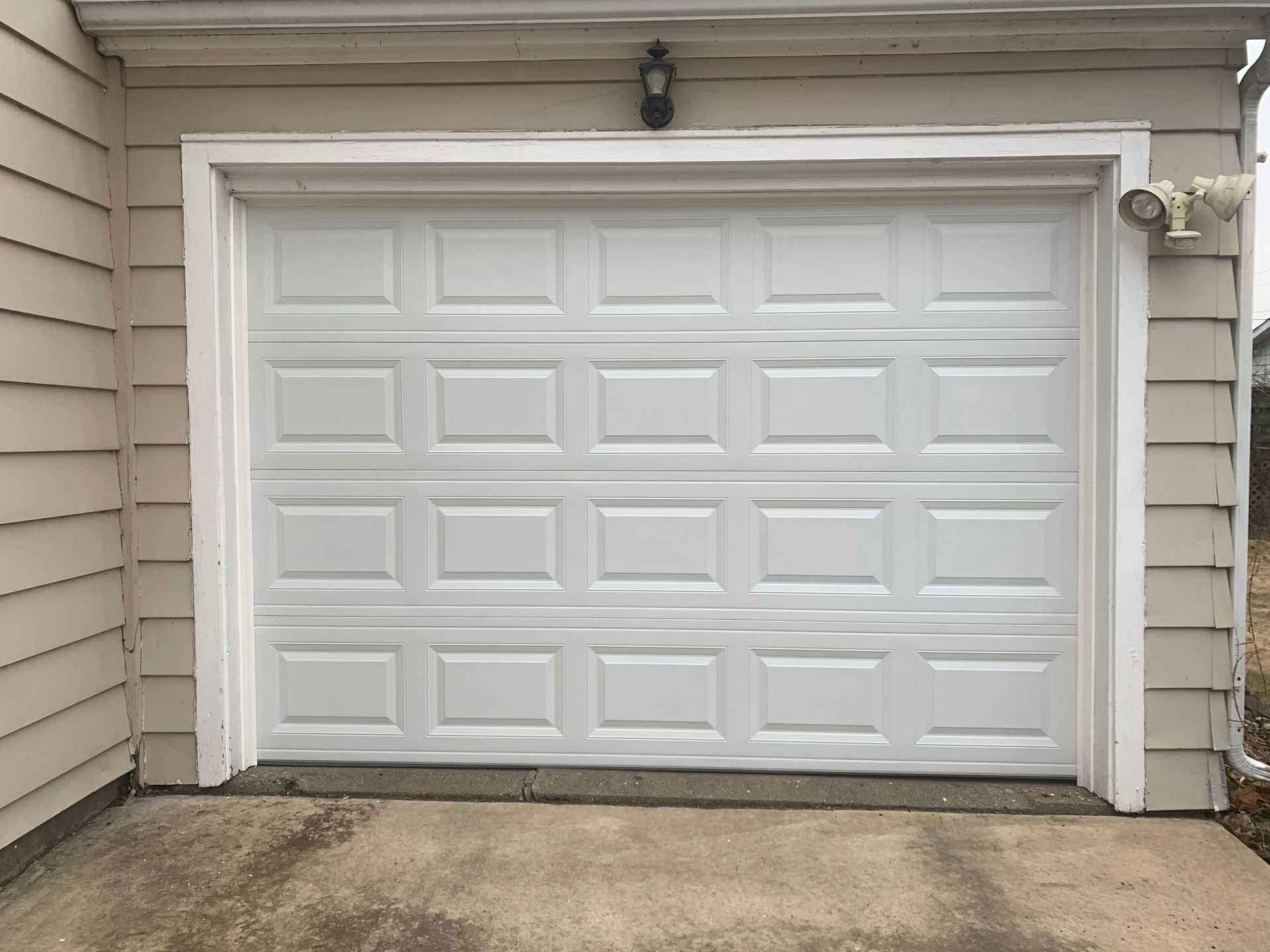 White garage door on a beige building with concrete.