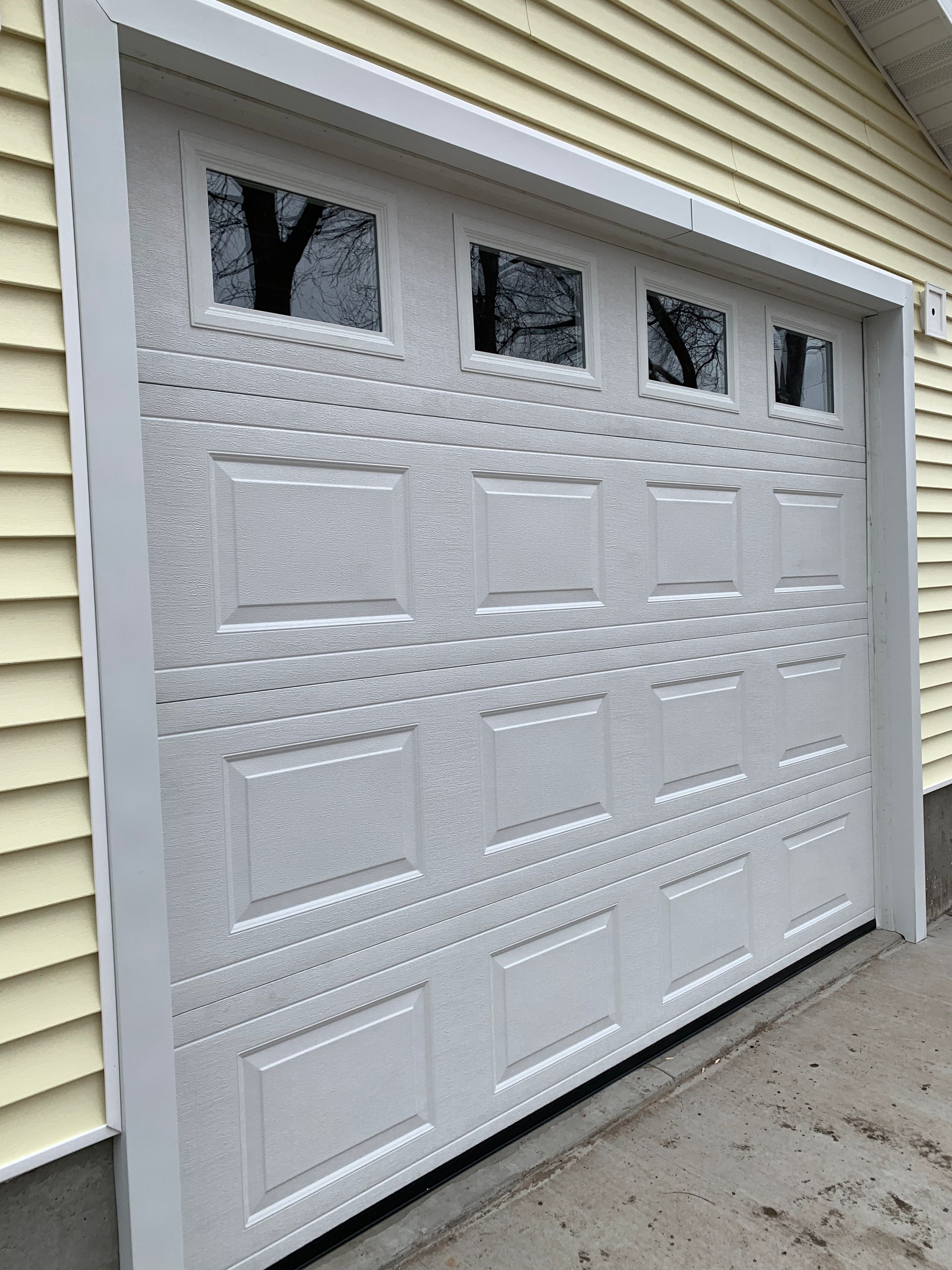 White garage door with windows on a yellow building.