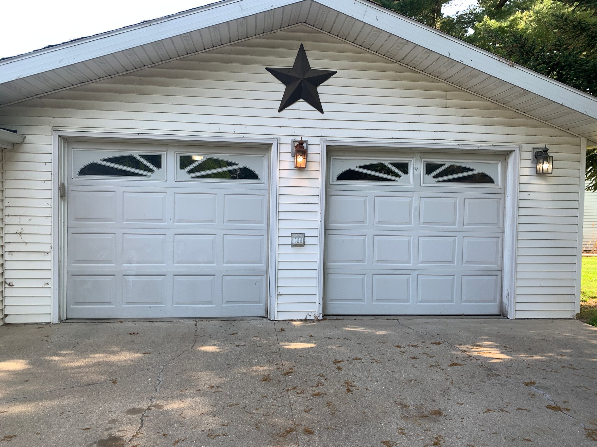 Two-car white garage with star decoration, two garage doors, and two sconce lights.