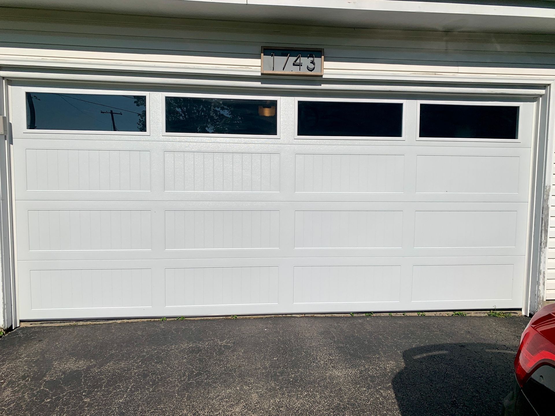 White garage door with four dark tinted windows and a house number 743 above.