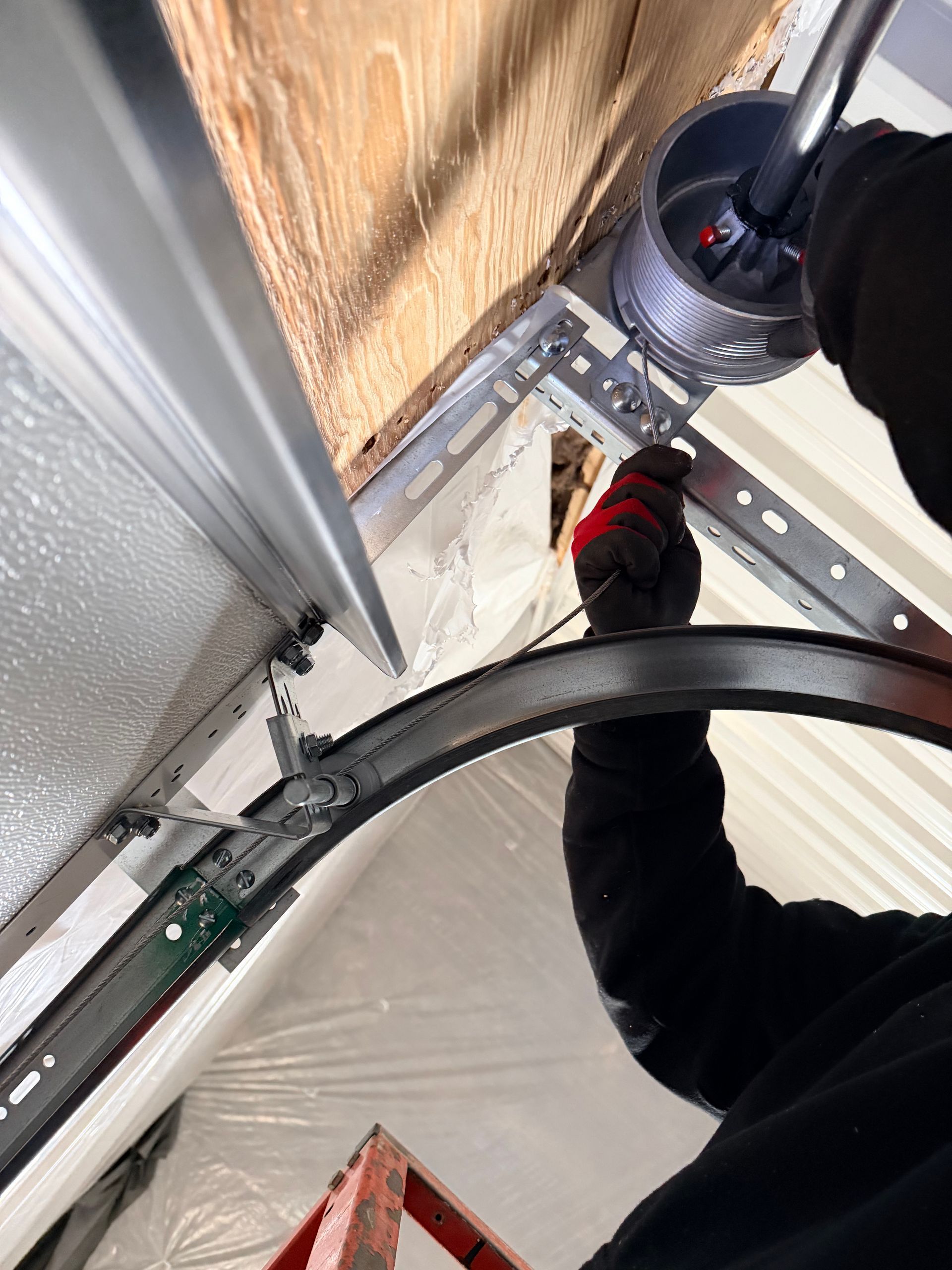 Garage door opener mounted on wooden beams, with a black motor unit and a chain drive.