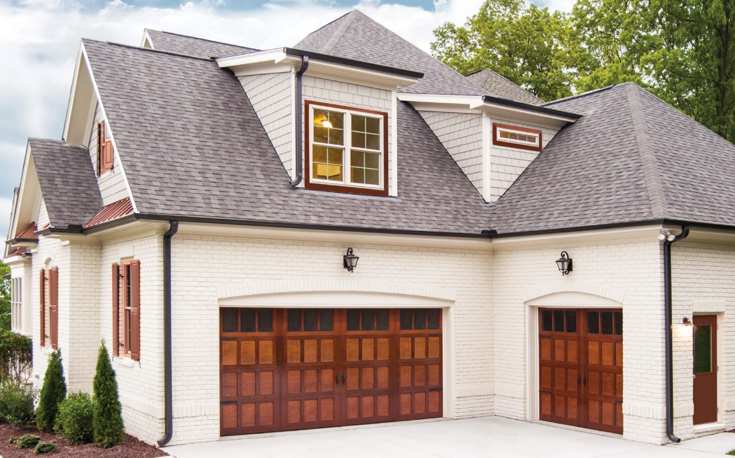 Two-car garage with white brick walls, dark wood doors, and a gray roof.