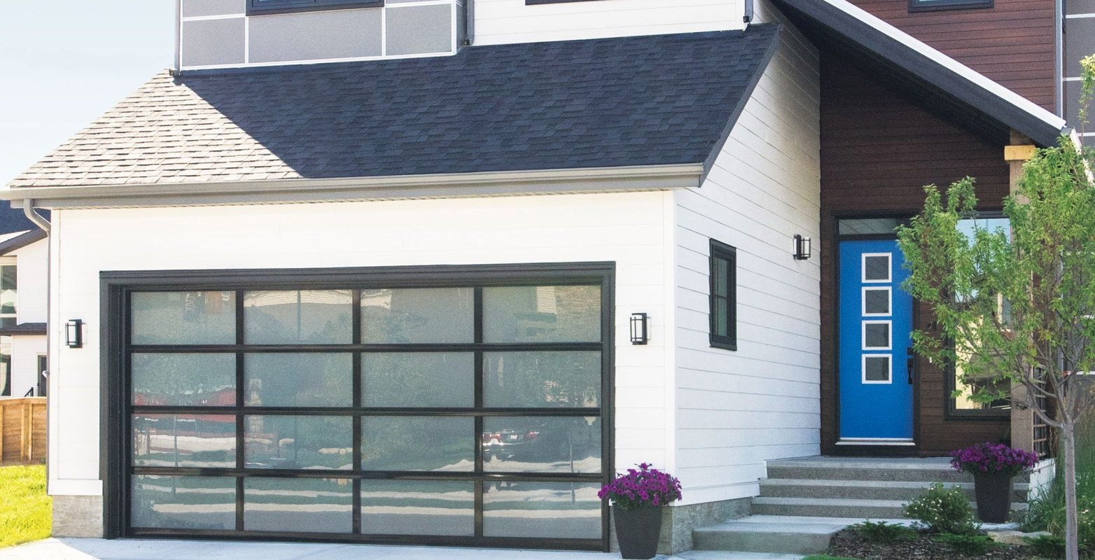 Modern white house with glass garage door, blue door, and dark roof.
