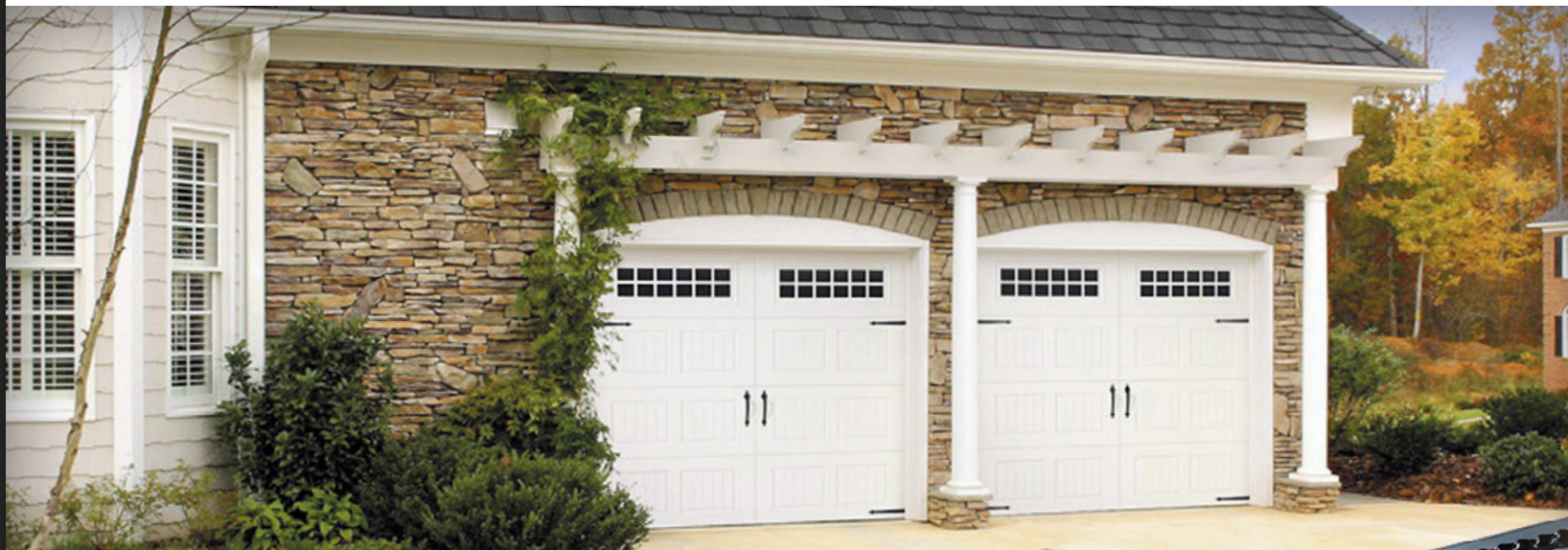 White garage doors with stone veneer and pergola.