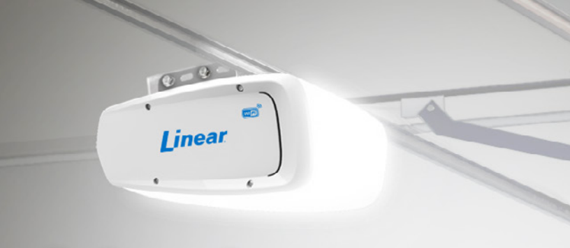 A white Linear garage door opener mounted on a white ceiling.