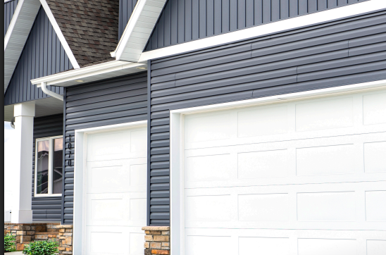 Dark blue siding on a house with white garage doors and trim.