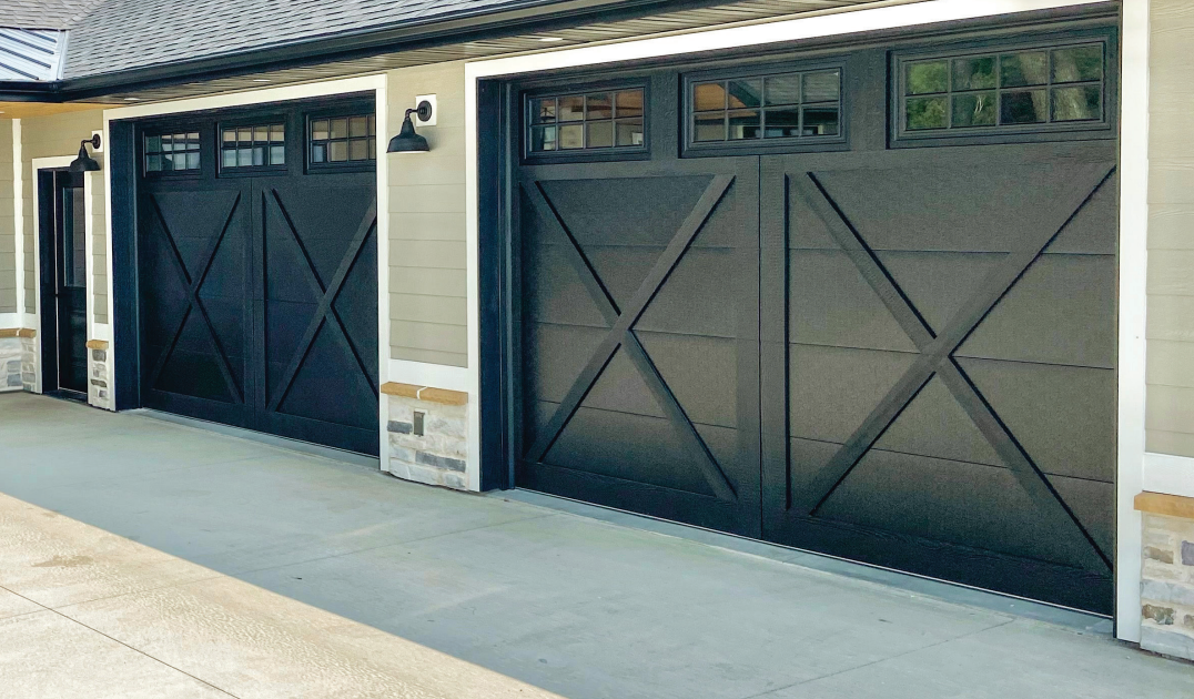 Black garage doors with crisscross design on beige house.