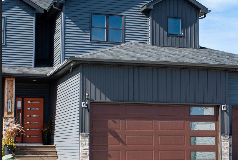 Dark blue house with brown garage door and front door; stone accents.