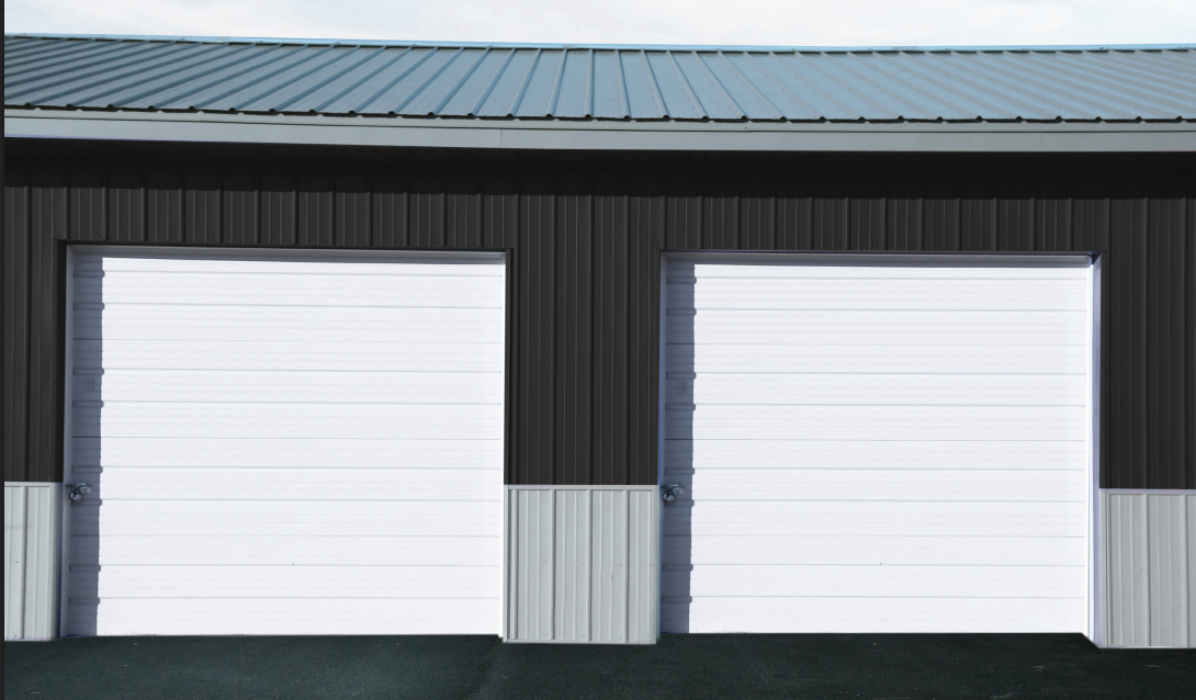 Two white garage doors in a black building with a blue roof.